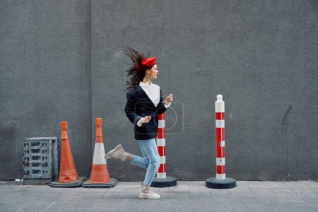 Photo for Fashion woman running down the street in front of the city tourist in stylish clothes with red lips and red beret, travel, cinematic color, retro vintage style, late to work. High quality photo - Royalty Free Image