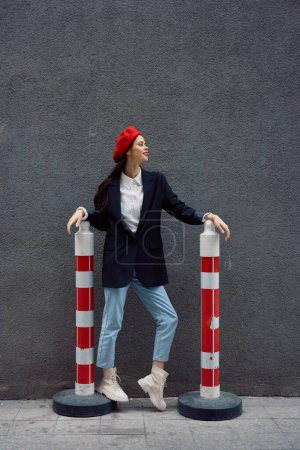 Foto de Mujer de moda de pie en la calle frente a la ciudad y la carretera trabaja turista en ropa elegante con labios rojos y boina roja, viajes, color cinematográfico, estilo vintage retro. Foto de alta calidad - Imagen libre de derechos