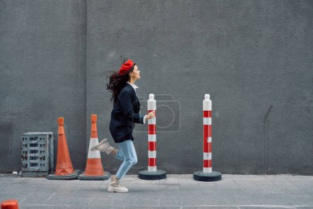 Foto de Mujer de moda corriendo por la calle frente al turista de la ciudad en ropa elegante con labios rojos y boina roja, viajes, color cinematográfico, estilo vintage retro. Foto de alta calidad - Imagen libre de derechos