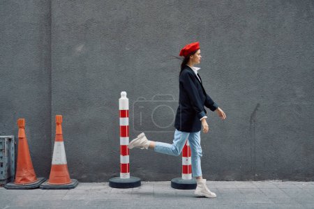 Photo for Fashion woman running down the street in front of the city tourist in stylish clothes with red lips and red beret, travel, cinematic color, retro vintage style, late to work, run. High quality photo - Royalty Free Image