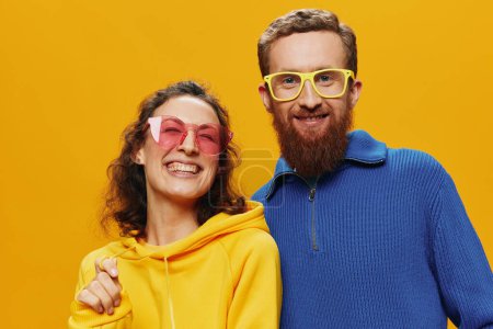 Téléchargez les photos : Couple homme et femme souriant joyeusement et tordu avec des lunettes, sur fond jaune, symboles signes et gestes de la main, tournage en famille, jeunes mariés. Photo de haute qualité - en image libre de droit
