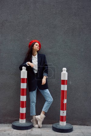 Photo for Fashion woman standing on the street in front of the city and road works tourist in stylish clothes with red lips and red beret, travel, cinematic color, retro vintage style. High quality photo - Royalty Free Image