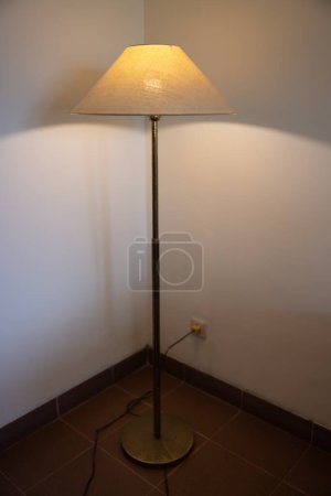 Foto de Interior con lámpara de pie y bombilla de resplandor en la oscuridad por la noche, una lámpara en la esquina contra una pared de lámpara de pie. Foto de alta calidad - Imagen libre de derechos