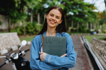 Photo for Woman smiling walking in the park outside with laptop freelancer against a backdrop of green palm trees in summer, tropical backdrop, blogger on a trip, work online. High quality photo - Royalty Free Image