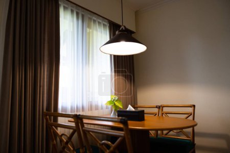 Foto de Interior de la casa oscura con mesa de comedor de madera iluminada por lámpara, luz de la noche para la cena. Foto de alta calidad - Imagen libre de derechos