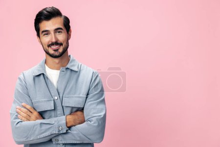 Foto de Retrato de un hombre moreno con estilo con una barba mirando a la cámara sobre un fondo rosa en una camiseta blanca y jeans sonrisa y emoción alegre en su cara, espacio de copia. Foto de alta calidad - Imagen libre de derechos