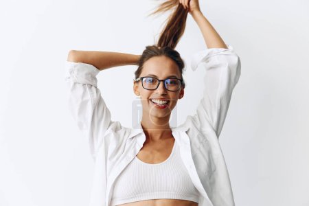 Téléchargez les photos : Portrait de femme avec peau bronzée portant des lunettes de vision sur un fond blanc souriant avec les dents et les mains en l'air dans la joie. Photo de haute qualité - en image libre de droit