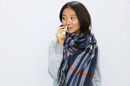 Téléchargez les photos : Femme asiatique grippe froide avec nez bouché détient pulvérisation nasale et pulvérise pulvérisation nasale pour les allergies et le virus covide 19 avec mal de gorge sur fond blanc. Photo de haute qualité - en image libre de droit