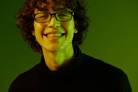 Photo for Man young man portrait close-up portrait in glasses fashion smile, hipster lifestyle, portrait green background mixed neon light, copy space. High quality photo - Royalty Free Image