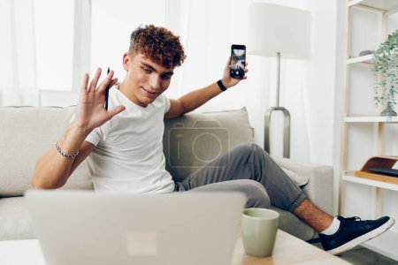Photo for Man interior message sofa smart selfies phone student smartphone sports young internet couch lifestyle technology curly teenager person cyberspace cellphone mobile home - Royalty Free Image