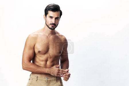 Photo for Male athlete model with a naked torso and six pack abs sporty inflated figure and tan on a white isolated background, fashionable clothing style, copy space, space for text. High quality photo - Royalty Free Image