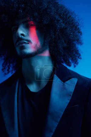 Foto de Retrato de moda de un hombre con el pelo rizado sobre un fondo azul, multinacional, de color claro, moderno concepto de moda. Foto de alta calidad - Imagen libre de derechos