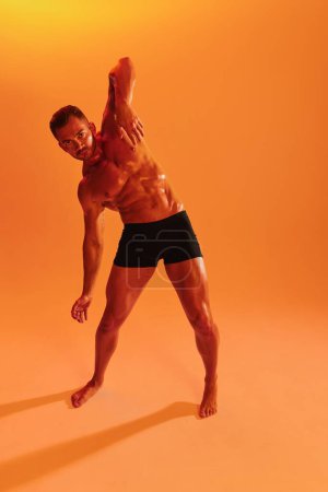 Téléchargez les photos : Homme bodybuilder boxer entraînement musculaire avec torse nu avec abdos posant en studio. Publicité, sport, mode de vie actif, lumière jaune colorée, compétition, concept de défi. . Photo de haute qualité - en image libre de droit