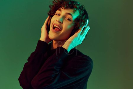 Photo for Man portrait in headphones listening to music, dancing and singing, DJ happiness and smile laughter, hipster teen lifestyle, portrait green background mixed neon light, copy space. High quality photo - Royalty Free Image