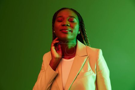 Photo for African american woman portrait business smile on green background in neon light, color mixed light, bright colors. Beauty African American woman with pigtails emotions. High quality photo - Royalty Free Image