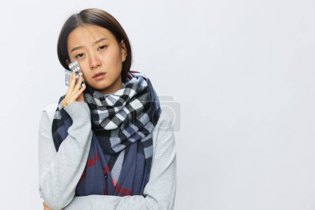 Téléchargez les photos : Femme asiatique maux de tête grippe froide tenant des médicaments et des pilules à carreaux avec fièvre malade de virus sur fond blanc, espace de copie. Photo de haute qualité - en image libre de droit