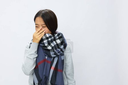 Téléchargez les photos : Femme asiatique grippe froide levé les mains contre les maux de tête et les maux de dents avec de la fièvre malade du virus covide 19 dans une écharpe à carreaux sur fond blanc, copiez l'espace. Photo de haute qualité - en image libre de droit