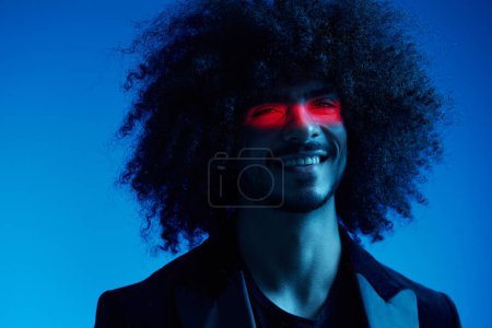 Photo for Fashion portrait of a man with curly hair on a blue background with a red stripe of light, multicolored light, trendy, modern concept. High quality photo - Royalty Free Image