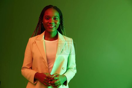 Foto de Mujer afroamericana retrato negocio sonrisa sobre fondo verde en luz de neón, color mezclado luz, colores brillantes. Belleza mujer afroamericana con coletas emociones. Foto de alta calidad - Imagen libre de derechos