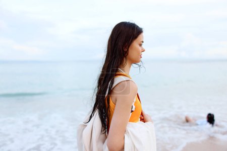 Téléchargez les photos : Jeune femme avec un sac à dos marche sur la plage, vacances d'été sur une île au bord de l'océan à Bali. Photo de haute qualité - en image libre de droit