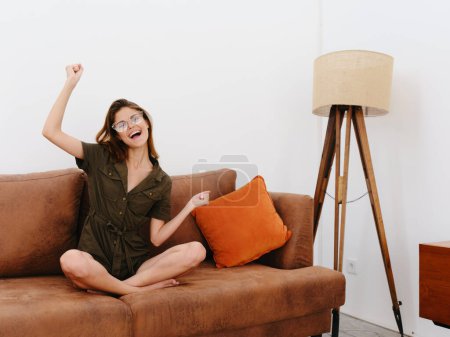 Photo for Woman model sitting on the couch at home smile, surprise, joy and relaxation, modern interior lifestyle, copy space, fall color palette. High quality photo - Royalty Free Image