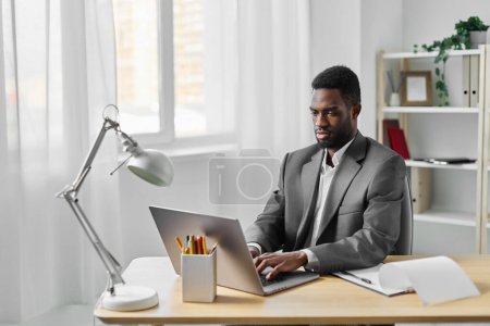 Foto de Estudiante hombre conferencia africano empresa freelance trabajo freelancer ordenador portátil sonriendo web en línea masculino educación interior trabajador chat tecnología lugar de trabajo oficina americana - Imagen libre de derechos