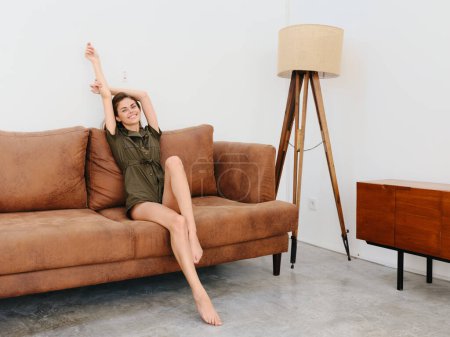 Foto de Mujer joven modelo sentada en el sofá en casa sonriente y relajante, estilo de vida interior moderno. Foto de alta calidad - Imagen libre de derechos