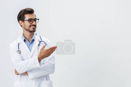 Téléchargez les photos : Homme médecin en manteau blanc et lunettes sourire montre des signes de gestes de la main sur fond blanc isolé regarde dans la caméra, espace de copie, espace pour le texte, la santé. Photo de haute qualité - en image libre de droit