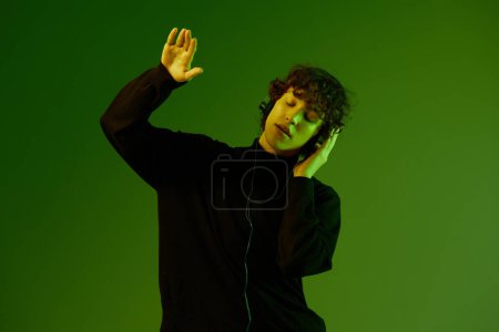 Photo for Man party with headphones listening to music, dancing and singing, DJ teenager happiness and smile, hipster lifestyle, portrait green background mixed neon light, copy space. High quality photo - Royalty Free Image
