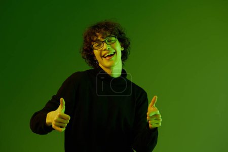 Téléchargez les photos : Homme jeune homme portrait en lunettes mode bonheur et sourire, mode de vie hipster, portrait fond vert mixte néon lumière, espace de copie. Photo de haute qualité - en image libre de droit