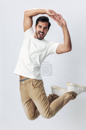 Foto de Hombre de moda saltando y corriendo en una camiseta blanca y jeans, sonrisa con dientes alegría sobre un fondo blanco aislado, estilo de ropa de moda, espacio de copia, espacio para el texto. Foto de alta calidad - Imagen libre de derechos