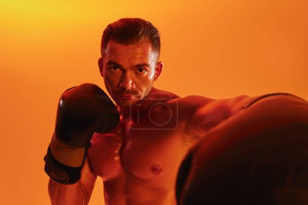 Téléchargez les photos : Homme bodybuilder boxer entraînement musculaire avec torse nu. Publicité, sport, mode de vie actif, lumière jaune colorée, compétition, concept de défi. . Photo de haute qualité - en image libre de droit