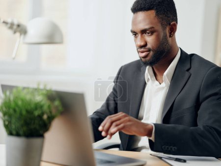 Photo for Man businessman cyberspace indoor freelancer student office american african computer desk online internet programmer job entrepreneur table call laptop african education distance - Royalty Free Image