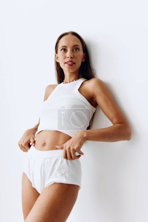 Photo for Beautiful woman model with tanned skin and a beautiful slender body and long hair posing on the white wall of the house in her underwear. High quality photo - Royalty Free Image