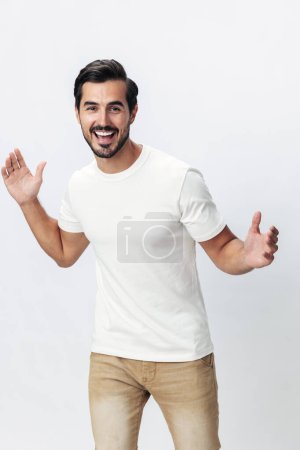 Téléchargez les photos : Modèle masculin en t-shirt blanc et jean, sourire avec des dents de joie sur un fond blanc isolé, style vestimentaire tendance, espace de copie, espace pour le texte. Photo de haute qualité - en image libre de droit