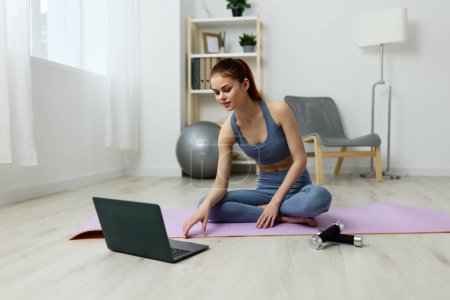 Téléchargez les photos : Femme lotus vidéo dame séance d'entraînement tapis style de vie vivre à la maison formation santé yoga salle de fitness étirement exercice intérieur bien-être ordinateur portable classe détente - en image libre de droit
