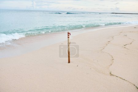 Téléchargez les photos : Vue sur la plage avec océan de sable et magnifique coucher de soleil sur l'île de Beli avec une marque pour mesurer la hauteur de l'eau. Photo de haute qualité - en image libre de droit