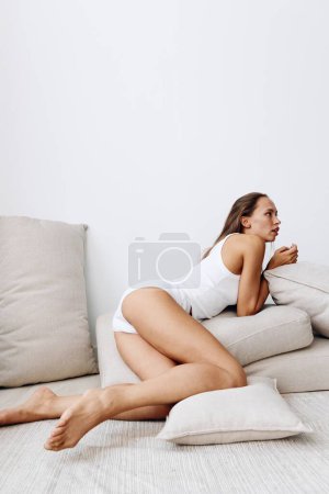 Foto de Hermosa modelo de mujer posa acostada sobre almohadas en el suelo con la piel bronceada limpiando su cuerpo, tratamientos de belleza en casa. Foto de alta calidad - Imagen libre de derechos