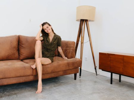 Foto de Mujer joven modelo sentado en el sofá en casa sonriente y relajante, estilo de vida interior moderno, espacio de copia. Foto de alta calidad - Imagen libre de derechos