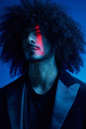 Foto de Retrato de moda de un hombre con el pelo rizado sobre un fondo azul, multinacional, de color claro, moderno concepto de moda. Foto de alta calidad - Imagen libre de derechos
