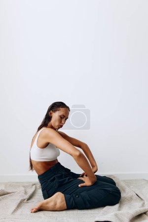 Foto de Mujer posa sentada sobre sus rodillas en el suelo con hermosa piel bronceada y largo cabello castaño. Foto de alta calidad - Imagen libre de derechos
