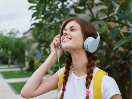 Photo for Woman happy college student traveling on vacation with backpack and headphones listening to music with a smile. High quality photo - Royalty Free Image