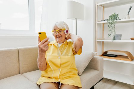 Foto de Mujer de edad avanzada feliz que mira en la sonrisa de la videollamada del teléfono, tecnología para la comunicación, interior moderno brillante, estilo de vida comunicación en línea. Foto de alta calidad - Imagen libre de derechos