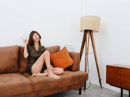 Photo for Woman model sitting on the couch at home smiling, thoughtful and relaxed, modern interior lifestyle, copy space, fall color palette. High quality photo - Royalty Free Image