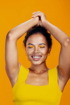 Téléchargez les photos : Femme colorée espace noir portrait cosmétique créatif belle copie peau modèle cosmétologie beauté studio sourire mode maquillage visage africain jaune - en image libre de droit