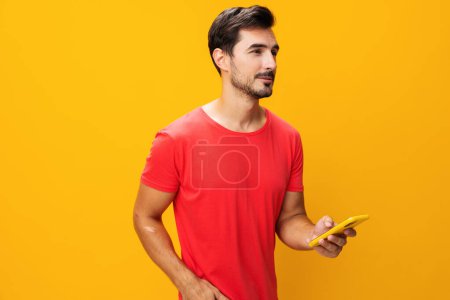 Photo for Cyberspace man mobile surprise studio smartphone yellow toothy smile happy phone technology communication copy lifestyle phone smiling portrait business pointing space message eyeglass - Royalty Free Image