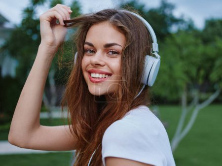 Photo for Woman wearing headphones listens to music smile with teeth as she travels through Asia. High quality photo - Royalty Free Image