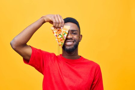 Téléchargez les photos : Homme espace pizza sourire fond rapide habitude gars jaune nutrition manger nourriture concept copie profiter adulte rouge mâle repas afro heureux noir livraison nourriture - en image libre de droit