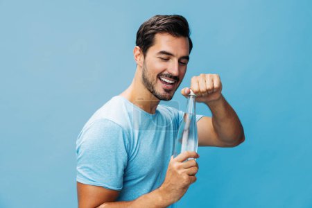 Photo for Cheerful man beauty smile sport holding t-shirt bottle drinking portrait isolated lifestyle sexy water studio healthy hand happy blue fresh drink background attractive - Royalty Free Image