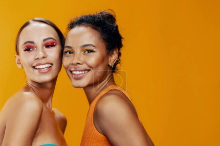 Téléchargez les photos : Femme américaine belle ensemble peau fille heureux race mixte beauté portrait briller africaine sain deux studio modèle maquillage coloré soin du corps visage jaune attrayant - en image libre de droit